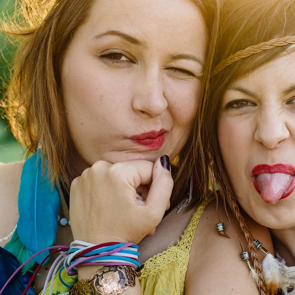 Close up fashion portrait of Two friends have fun , make grimaces ,fun emotions and shows hand signs. Pretty girls wearing summer clothes