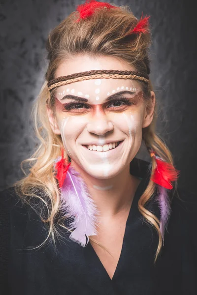 American Indian with paint face camouflage, smiling and looking into camera - studio photo with professional makeup