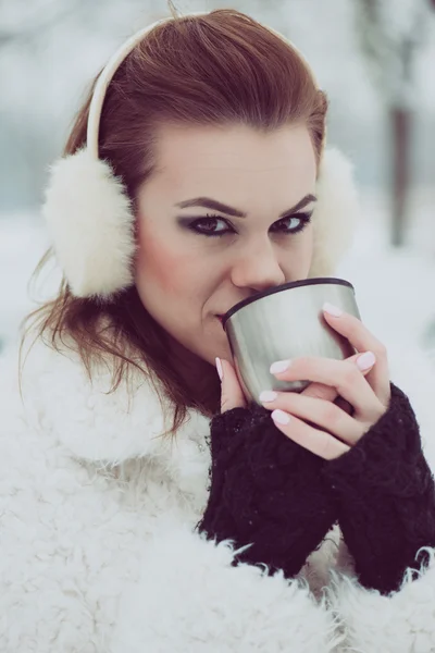 Close up portrait of young woman drinking hot tea or coffee outdoor, vintage winter vacation concept
