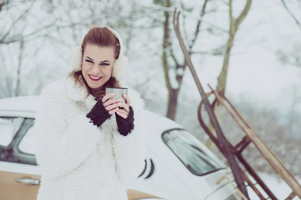 Young woman drinking hot tea or coffee outdoor, vintage winter vacation concept