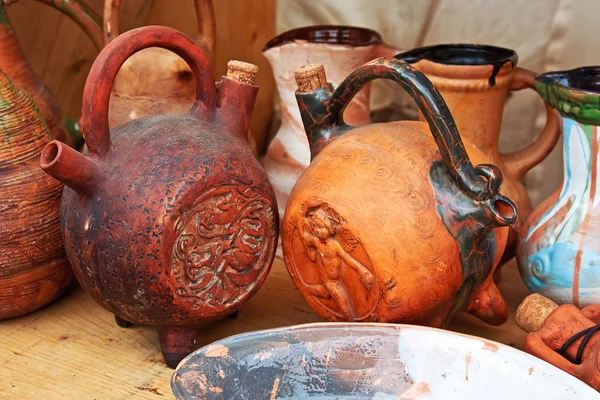 Clay folk jugs stand on a shelf. Rural handmade, craft, ceramics, ethnic, folk pitchers.