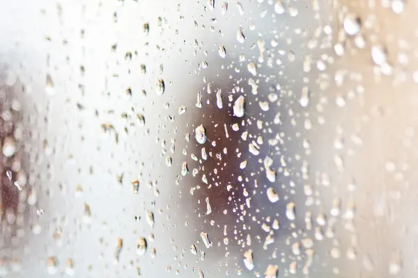 Stream of water in heavy rain. Raindrops on window pane. Blur effect.