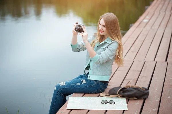 Pretty young woman traveling with photo camera and making pictures