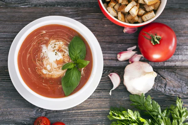 Delicious tomato soup with aromatic spices on a wooden table.