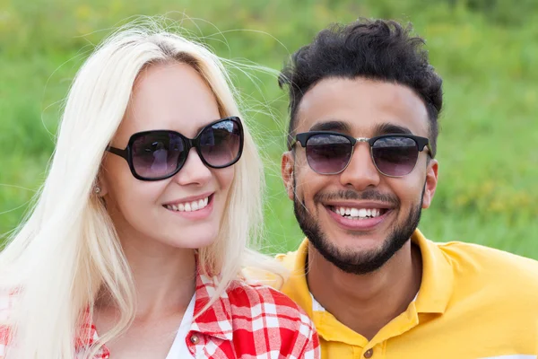 Couple face close up outdoor green grass, mix race man and woman sunglasses