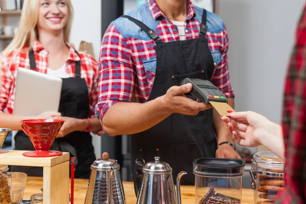 Close up credit card payment coffee shop bar counter barista serving client