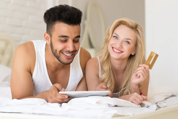 Young Couple Lying In Bed Using Tablet Computer Hold Credit card Online Shopping Payment