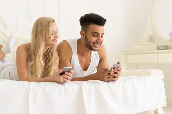 Young Couple Lying In Bed, Happy Smile Hispanic Man And Woman Using Cell Smart Phone