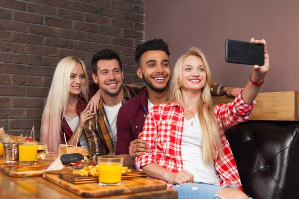 People Group Eating Fast Food Burgers Potato Sitting At Wooden Table In Cafe Taking Selfie Photo