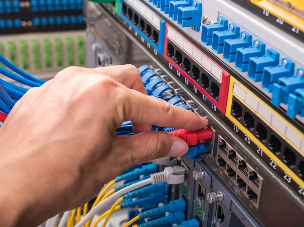 Man working in network server room with fiber optic hub for digi