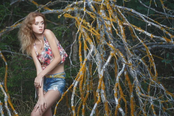 Young sexy model posing near old branches