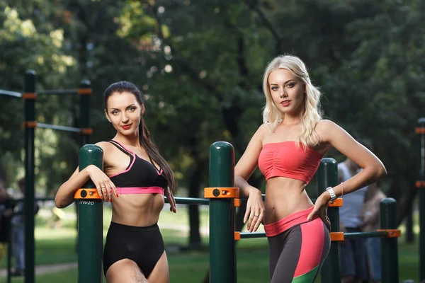 Young strong girls do exercises during street workout