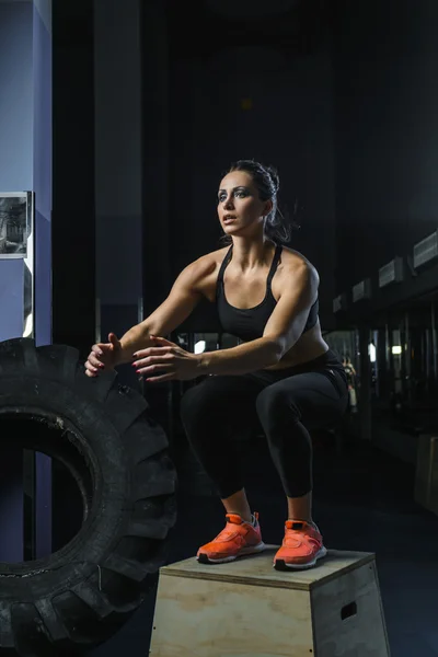 Powerful muscular woman CrossFit trainer jumps during workout at gym