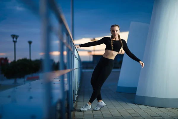Attractive fitness girl do workout at modern urban area sunset