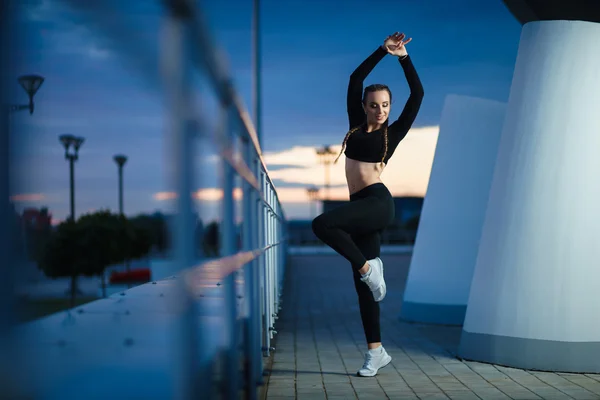 Attractive fitness girl do workout at modern urban area sunset