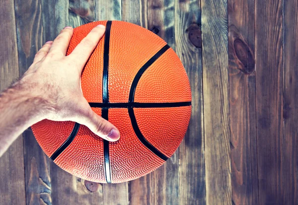 Basketball ball on wooden hardwood floor grabbing by hand.