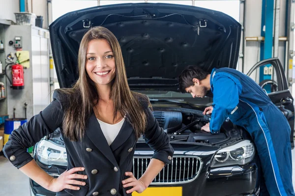 Businesswoman with mechanic repairing car