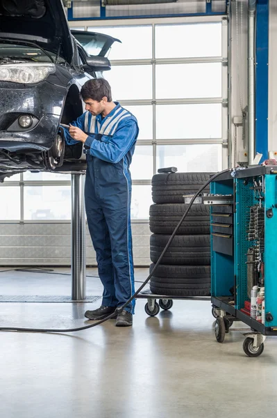 Mechanic repairing brake of lifted automobile