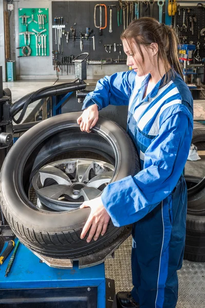 Female  mechanic mounting car tire