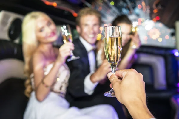Rich people drinking champagne in a limousine