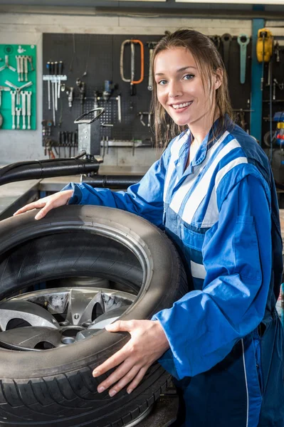 Female mechanic mounting car tire