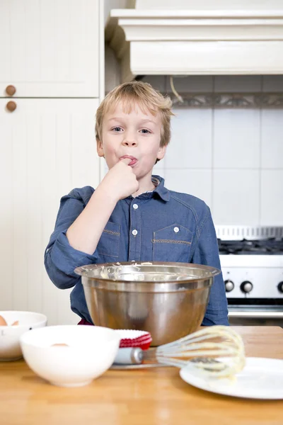 Licking batter from a bowl in a kitchen