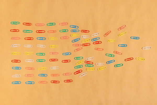 Flat lay colorful paper clips arrangement on kraft paper backgro