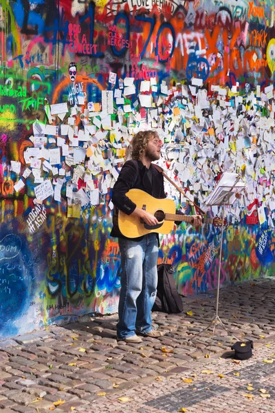 Street Busker performing in front of John Lennon Graffiti Wall