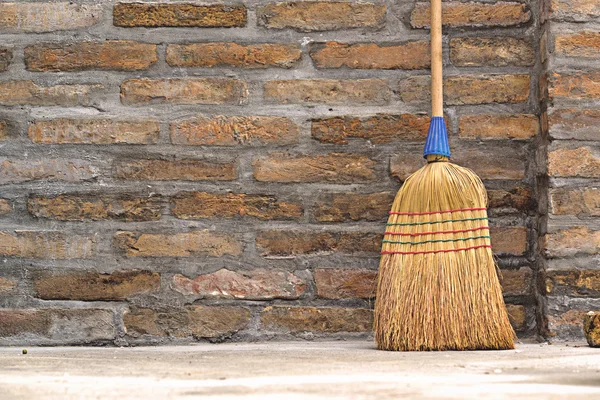 Household Broom For Floor Cleaning Leaning on Brick Wall