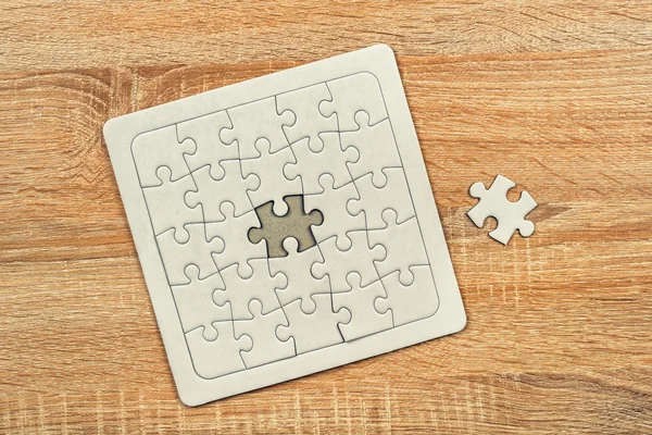 Piece missing from jigsaw puzzle on wooden table