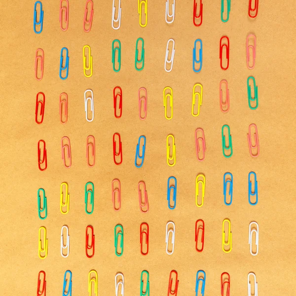 Flat lay colorful paper clips arrangement on kraft paper backgro