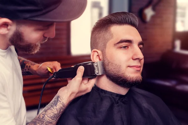 Young man having beard shaven