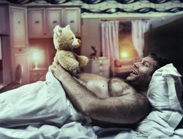 Man in bed looks at toy bear
