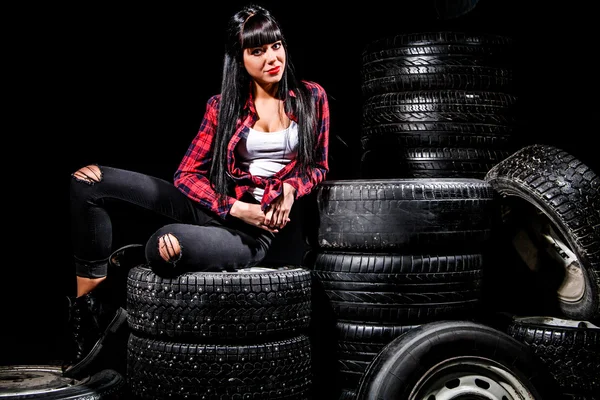 Young woman in a red checked shirt sitting on a tires