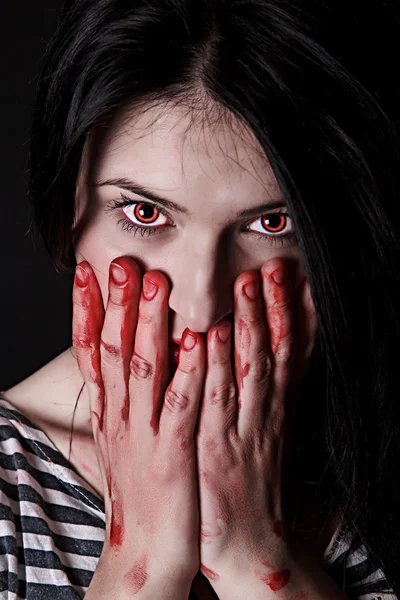 Woman with red eyes and bloody palms on her face
