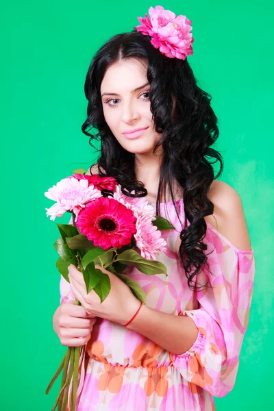 Beautiful young brunette in a pink dress with a bunch of gerbera