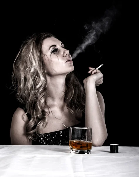 Depressed young woman with a glass of whiskey and a cigarette