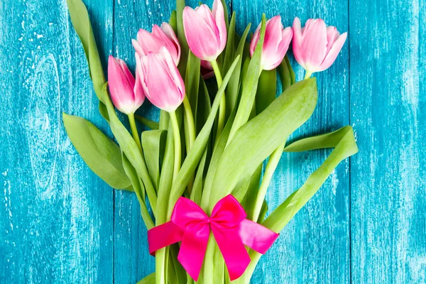 Beautiful pink tulips on blue wood background