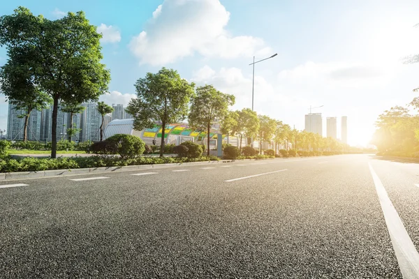 Empty asphalt road in modern city at sunrise