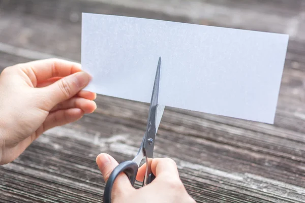 Woman cutting paper by scissors