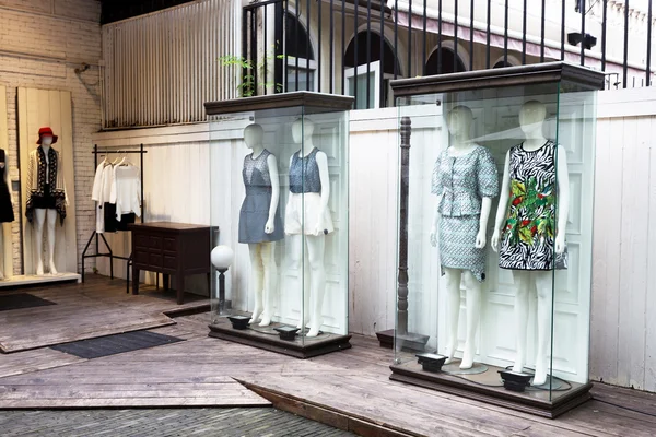 Mannequins stand in storefront glass box