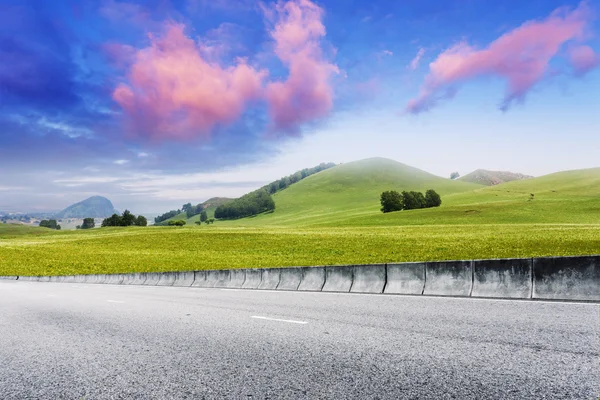 Road through meadow with cloud and sky