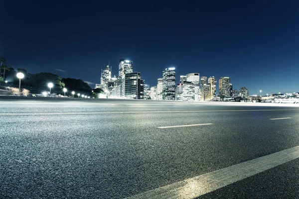 Empty road and illuminated modern cityscape
