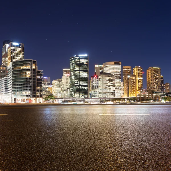 Empty road and illuminated modern cityscape