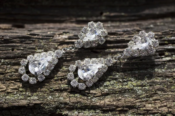 Pair of diamond earrings on brown wooden texture