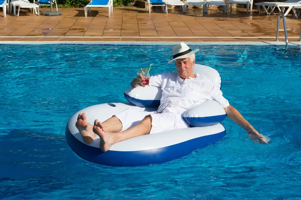 Wealthy man floating in swimming pool