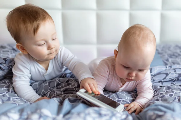 Baby boy and girl twins with smartphone