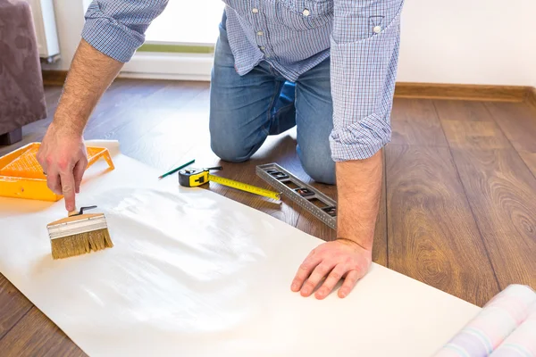 Handyman applying blue for a wallpaper