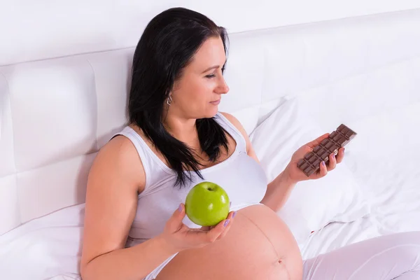 Pregnant woman with apple and chocolate