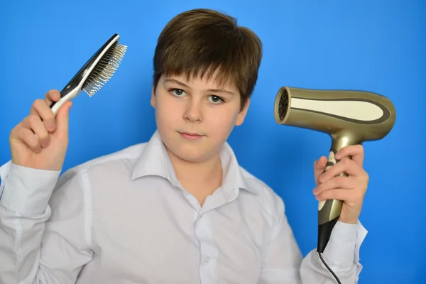 Boy teenager with comb and a hair dryer
